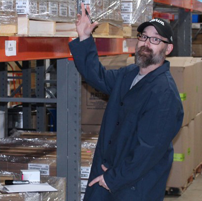 An EMS staff member standing in a warehouse waving
