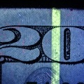 Detail of fluorescent strip and fluorescent fibers in a US $20 bill